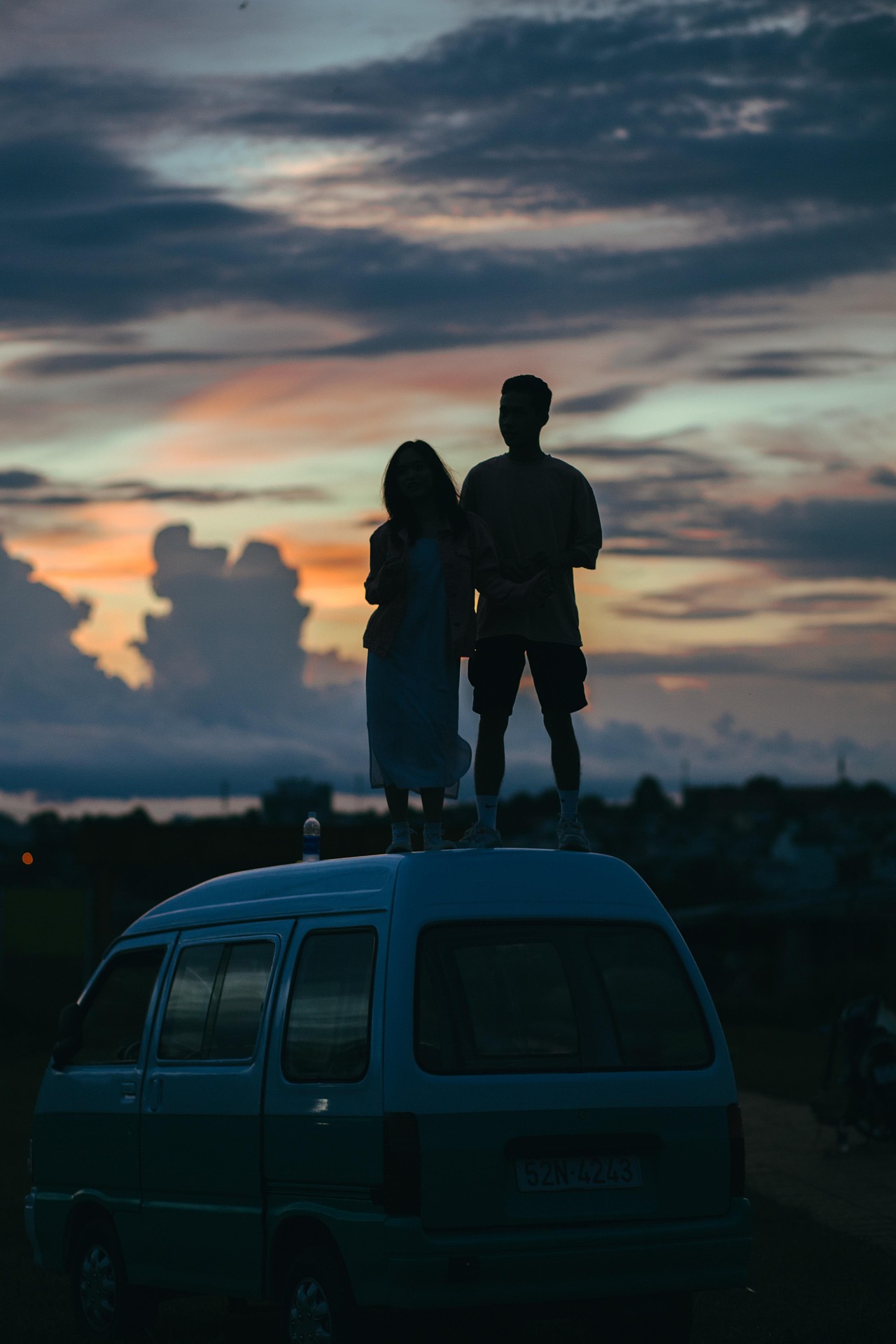 Image of a couple stood on a car looking at the sunset