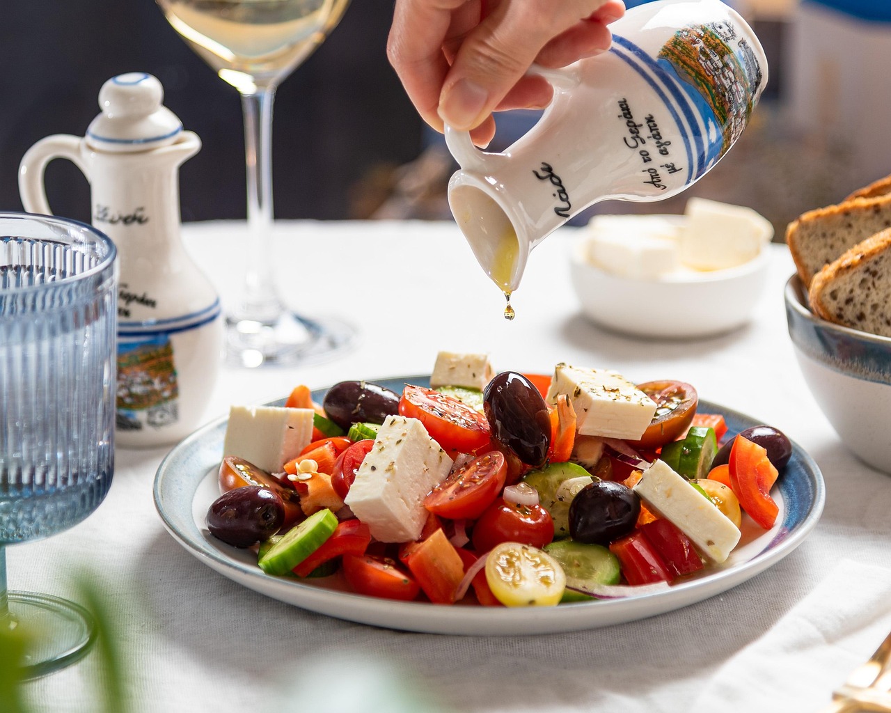 Image of a waiter pouring olive oil over a Greek salad
